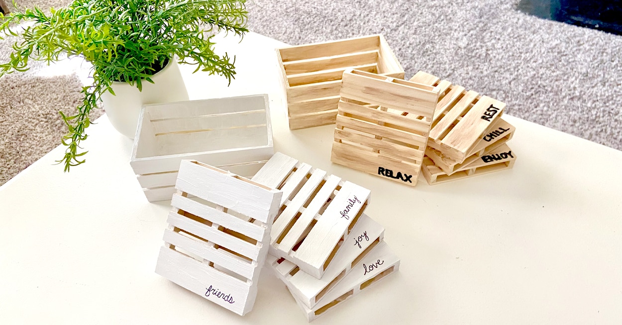 2 sets of 4 miniature pallet coasters displayed on a table. One set is