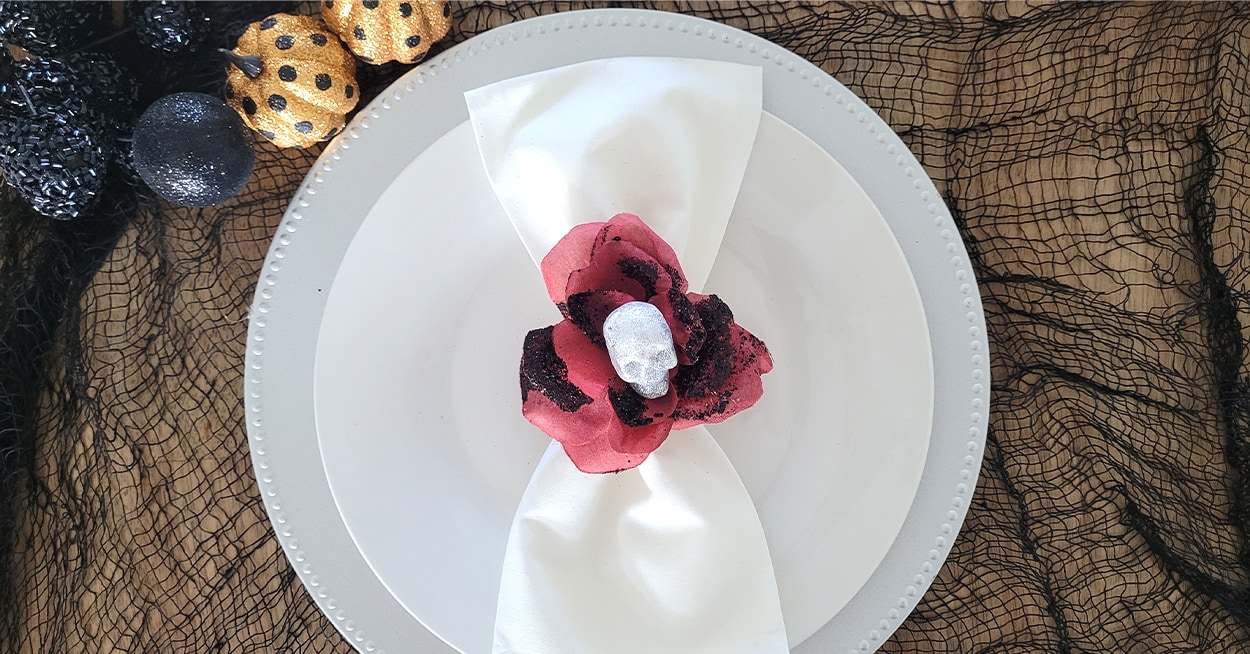 glittery pumpkins on black draping with a plate with white napkin with