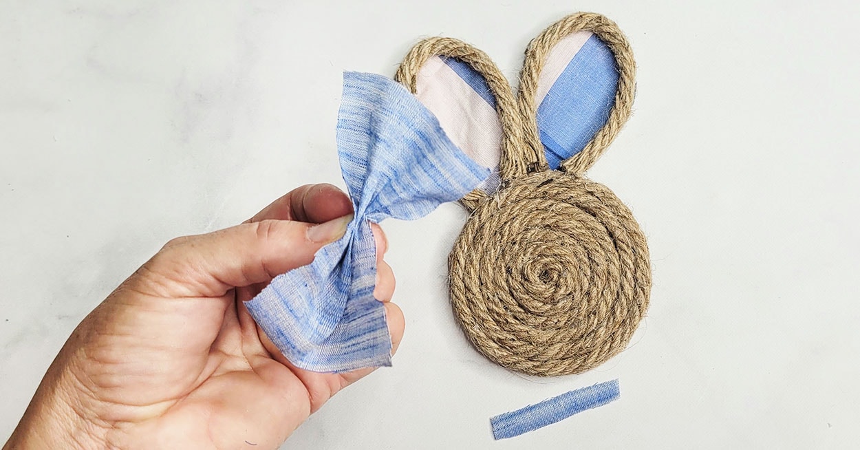 A nautical rope coaster shaped like a bunny and a hand holding a bow ...