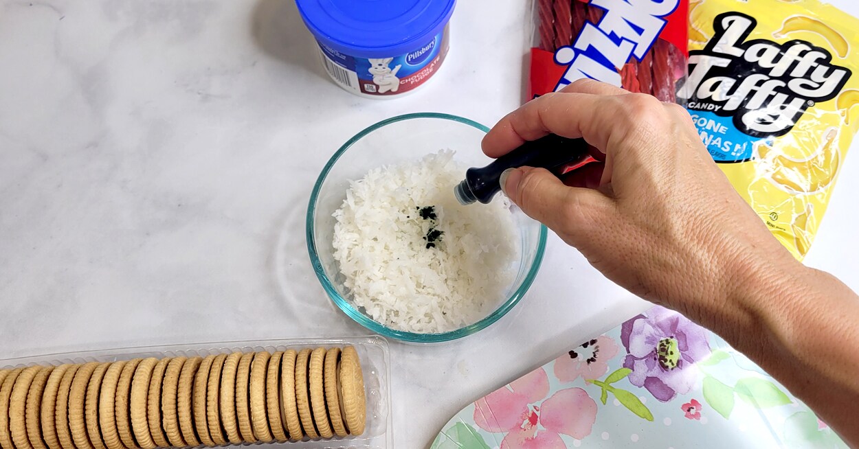 A hand dropping food coloring into a bowl of coconut flakes, pack of ...