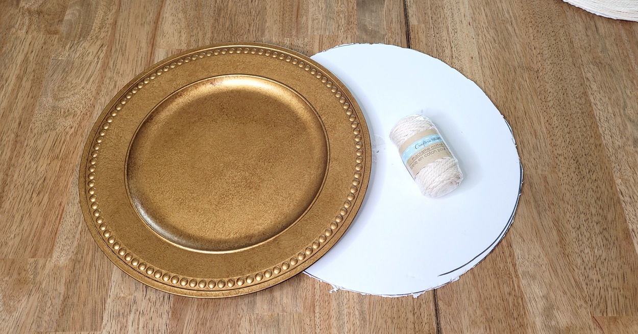 A gold charger, a round piece of foam board and a roll of macrame cotton twine.