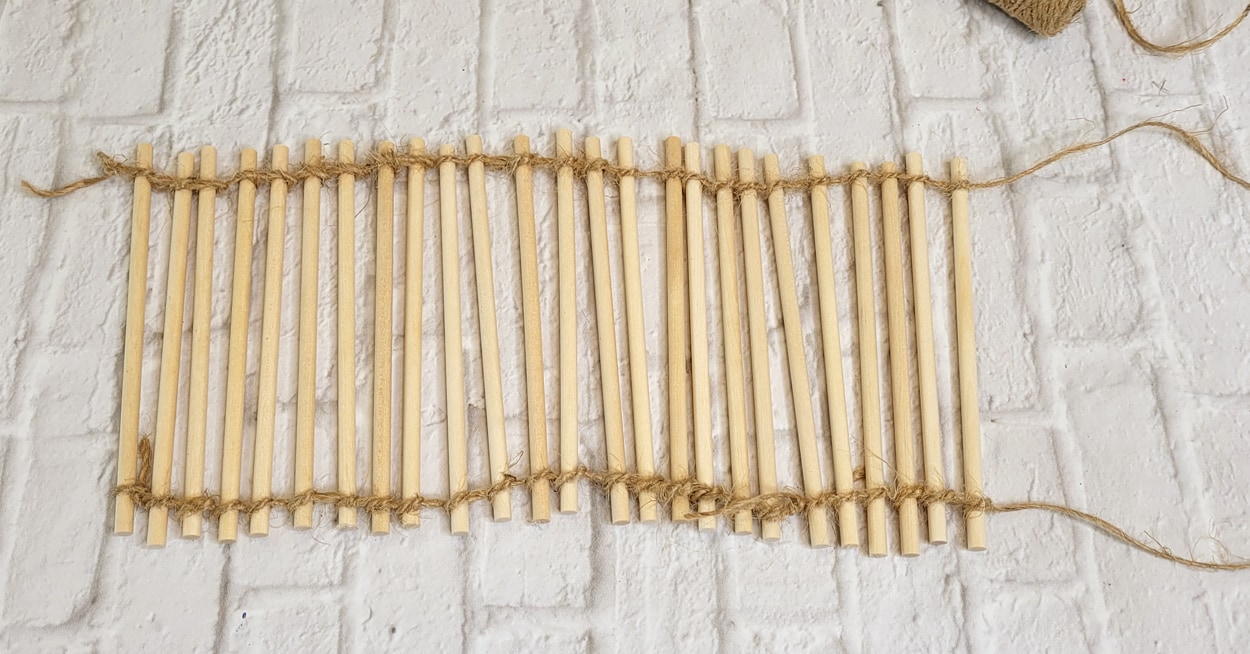 Wooden dowel rods with twine wrapped around the top and bottom of them.