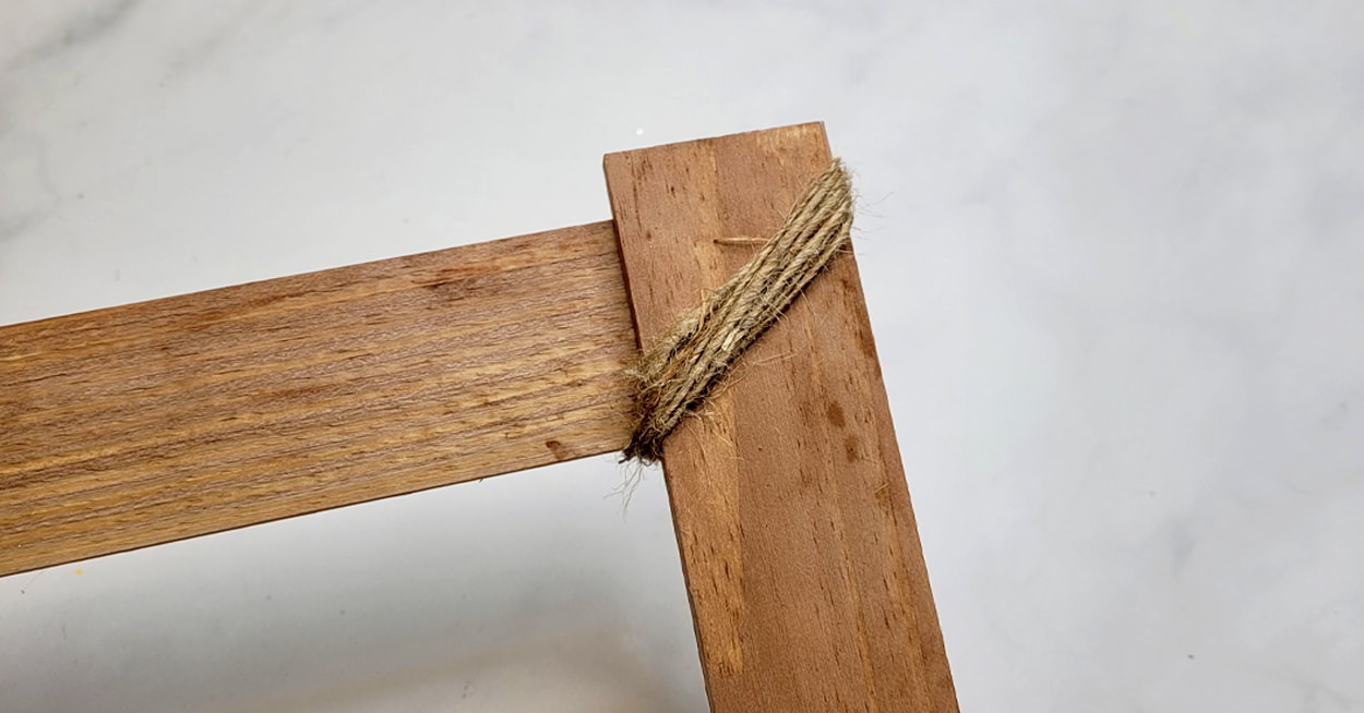 The corner of a wooden ladder with twine on it.