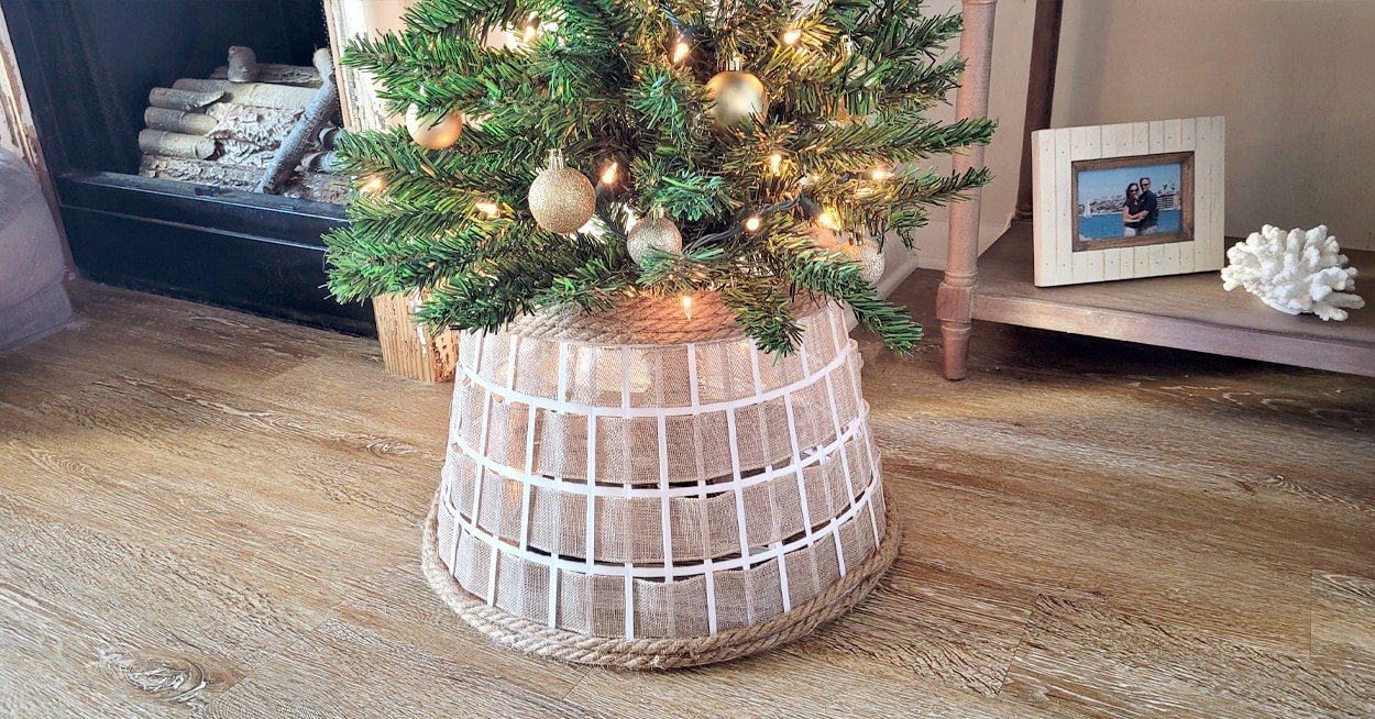 The bottom of a Christmas tree with a burlap tree collar around it.