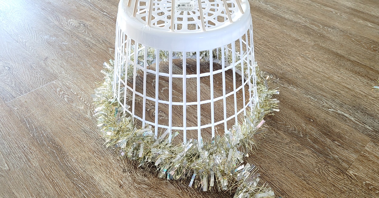 The bottom of a white laundry basket with gold and silver tinsel