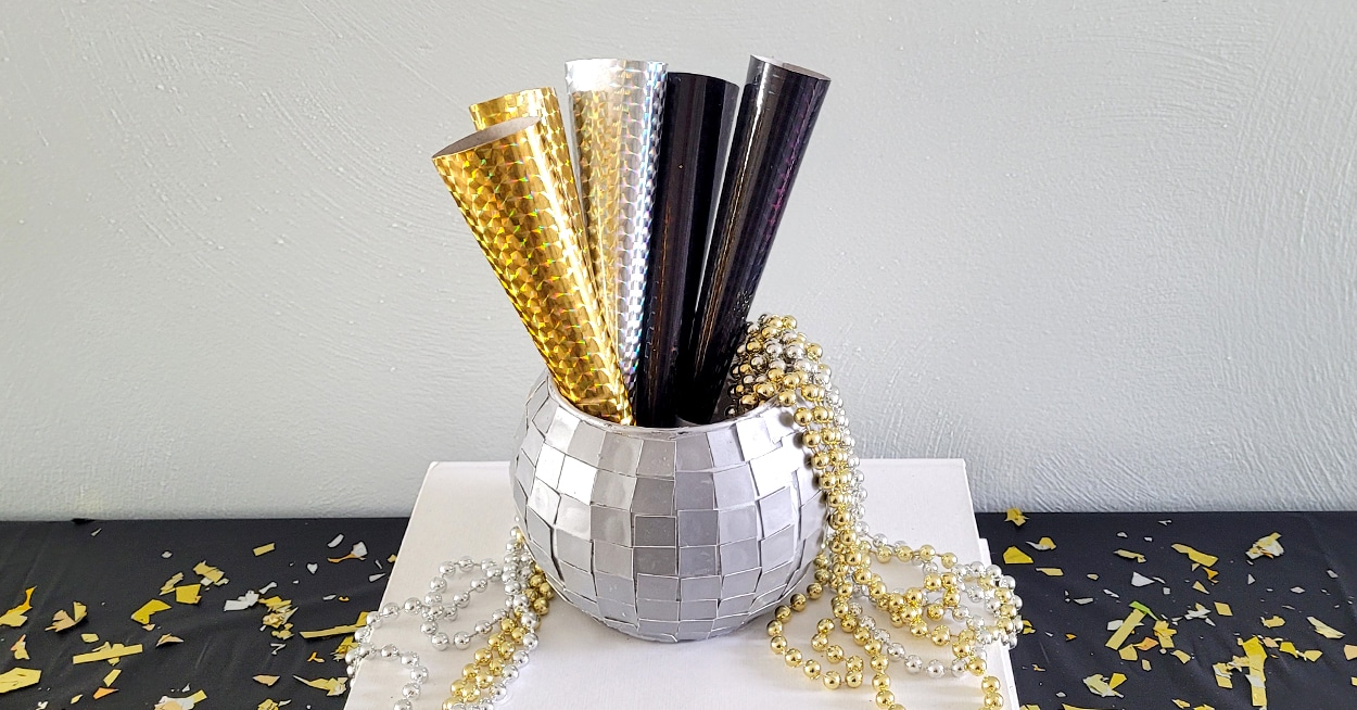 A disco ball vase with gold and black party horns and beads in it
