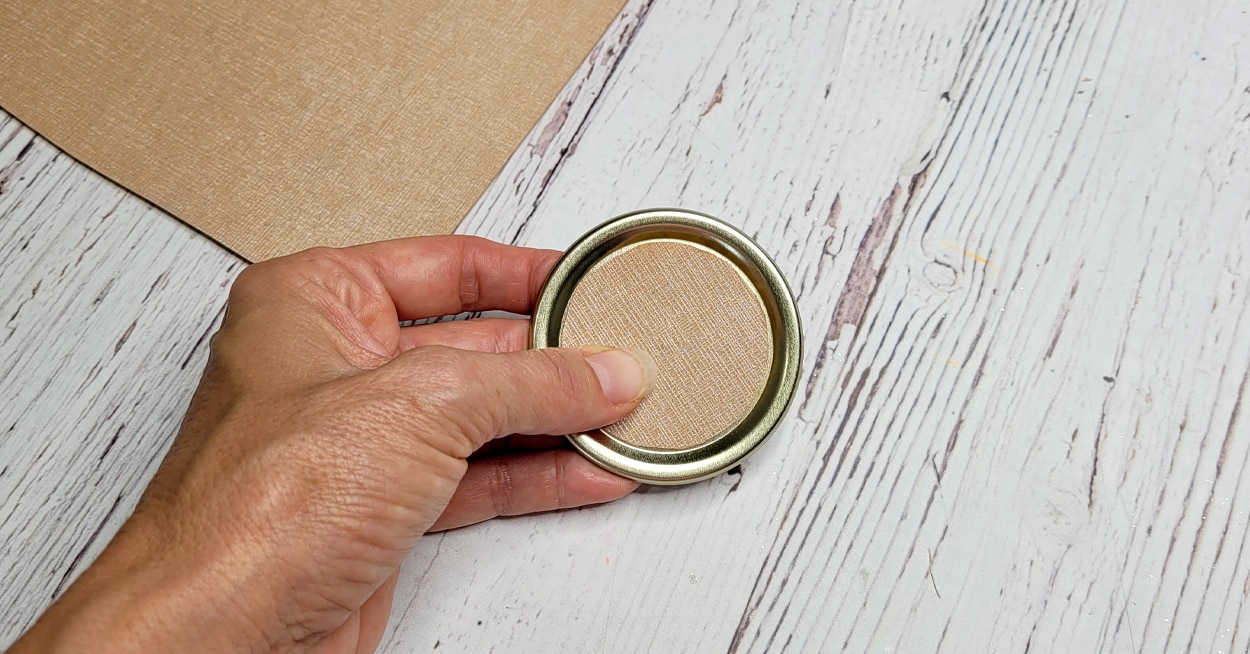 A hand holding a canning jar like with cardstock on it.