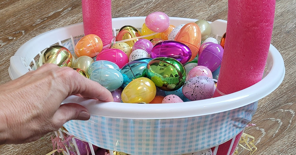 A hand holding glue and white ribbon making a bow.